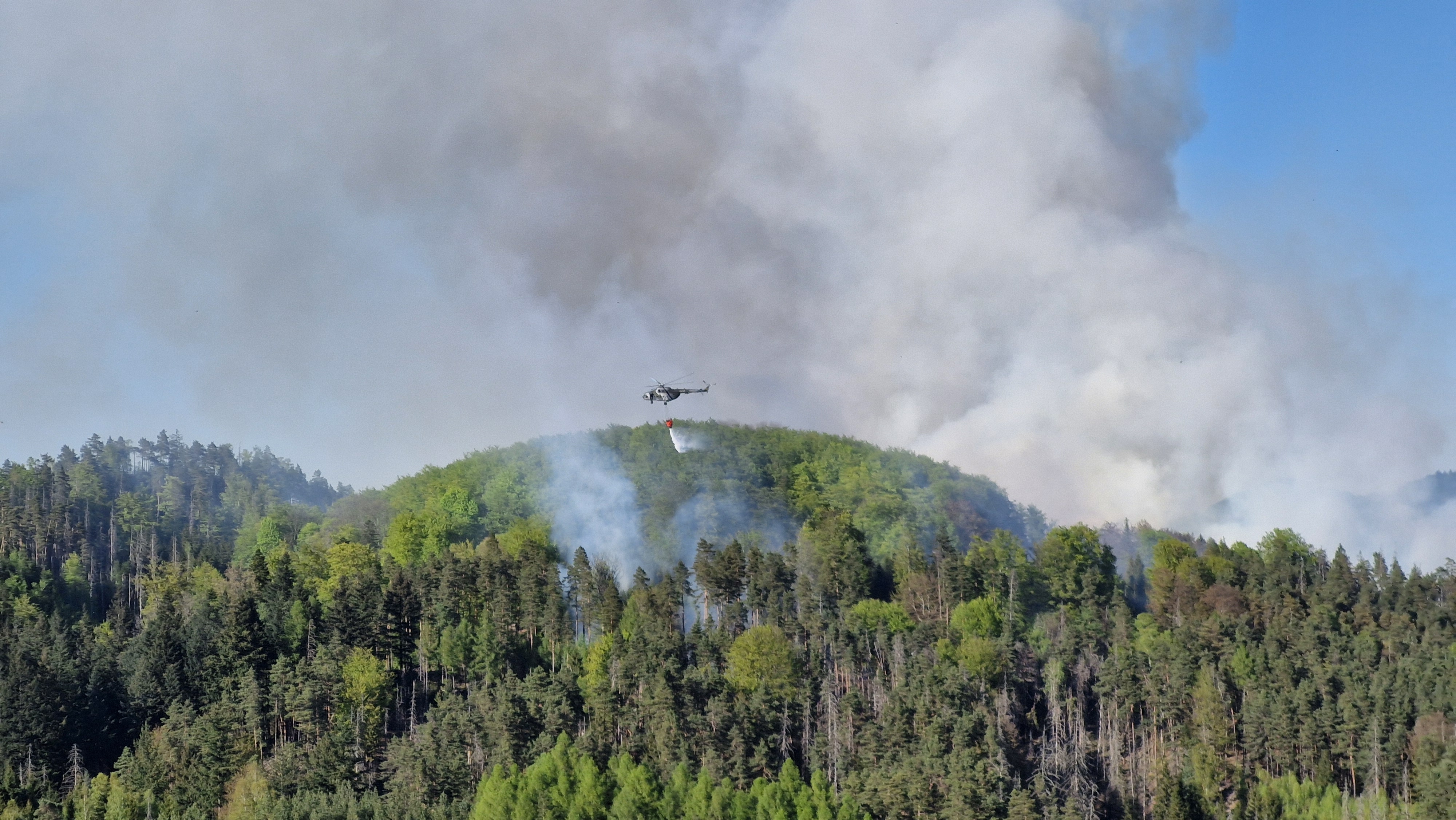Kouřový oblak z požáru před 18. hodinou, kdy již byly nasazeny dva vrtulníky. Foto: Tomáš Salov